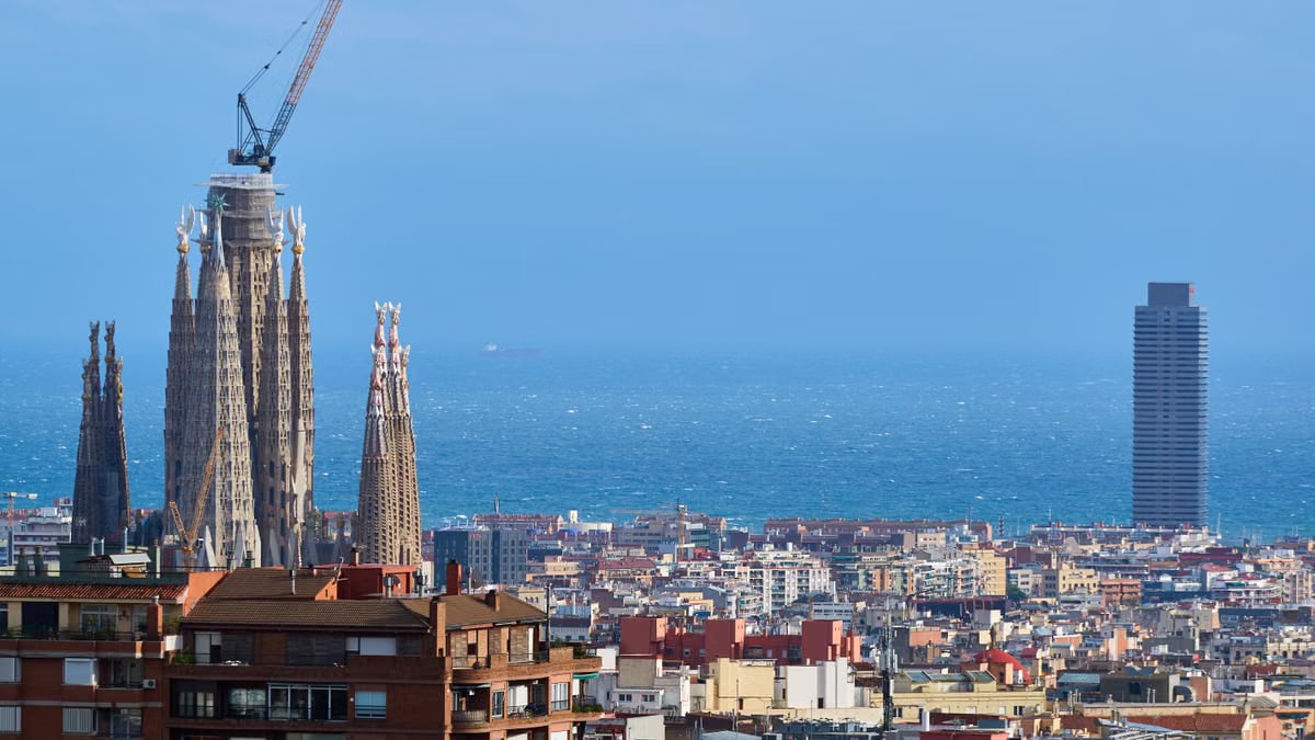 A vibrant view of Barcelona's skyline with La Sagrada Familia and the Mediterranean Sea in the background.